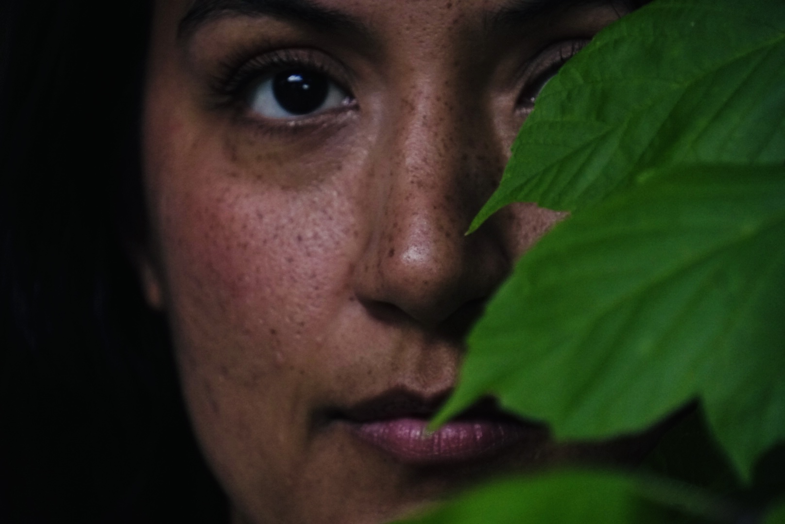Moody close-up portrait with leaves framing one eye